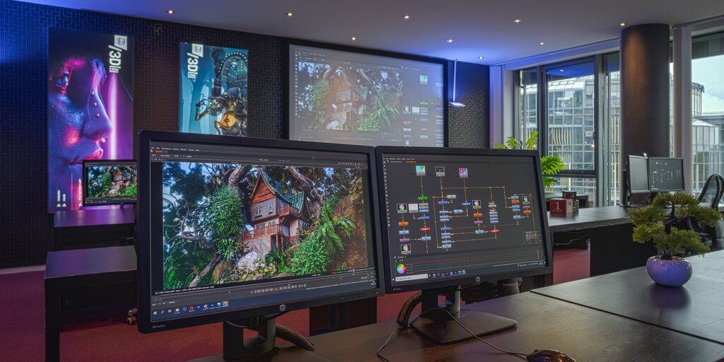 Two monitors display a compositing setup featuring a rendered 3D treehouse and a node graph in a modern training environment with projection screen, poster walls, and a city view through the windows.